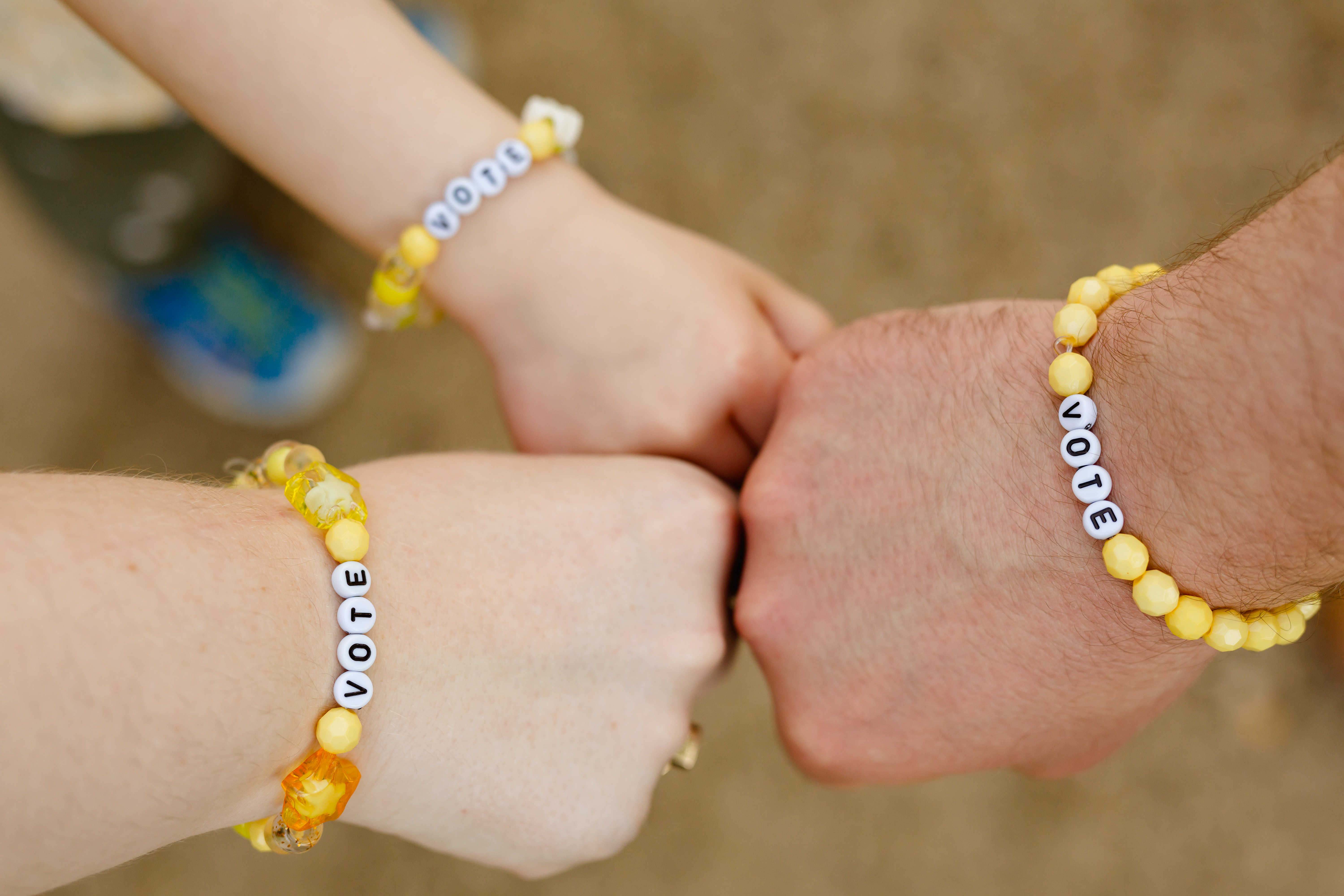 A team of hands with bracelets reading 'Vote'
